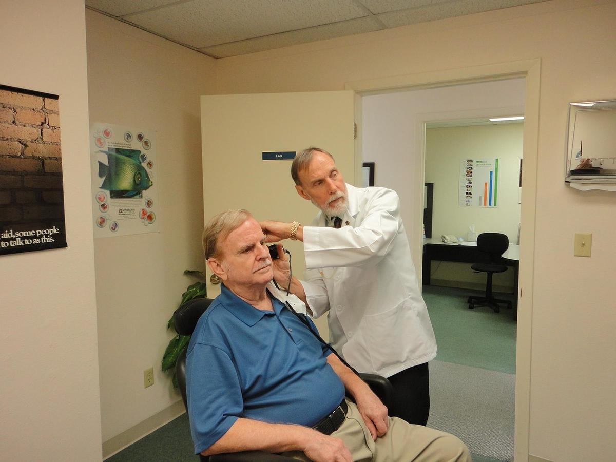 Médecin en blouse blanche examinant l'oreille d'un patient avec un otoscope dans un cabinet médical Médecin en blouse blanche examinant l'oreille d'un patient avec un otoscope dans un cabinet médical