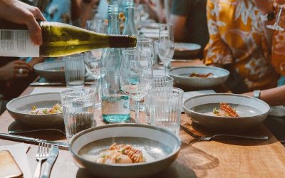 Groupe de personnes assises autour d'une table, repas en cours, verres et plats sur la table